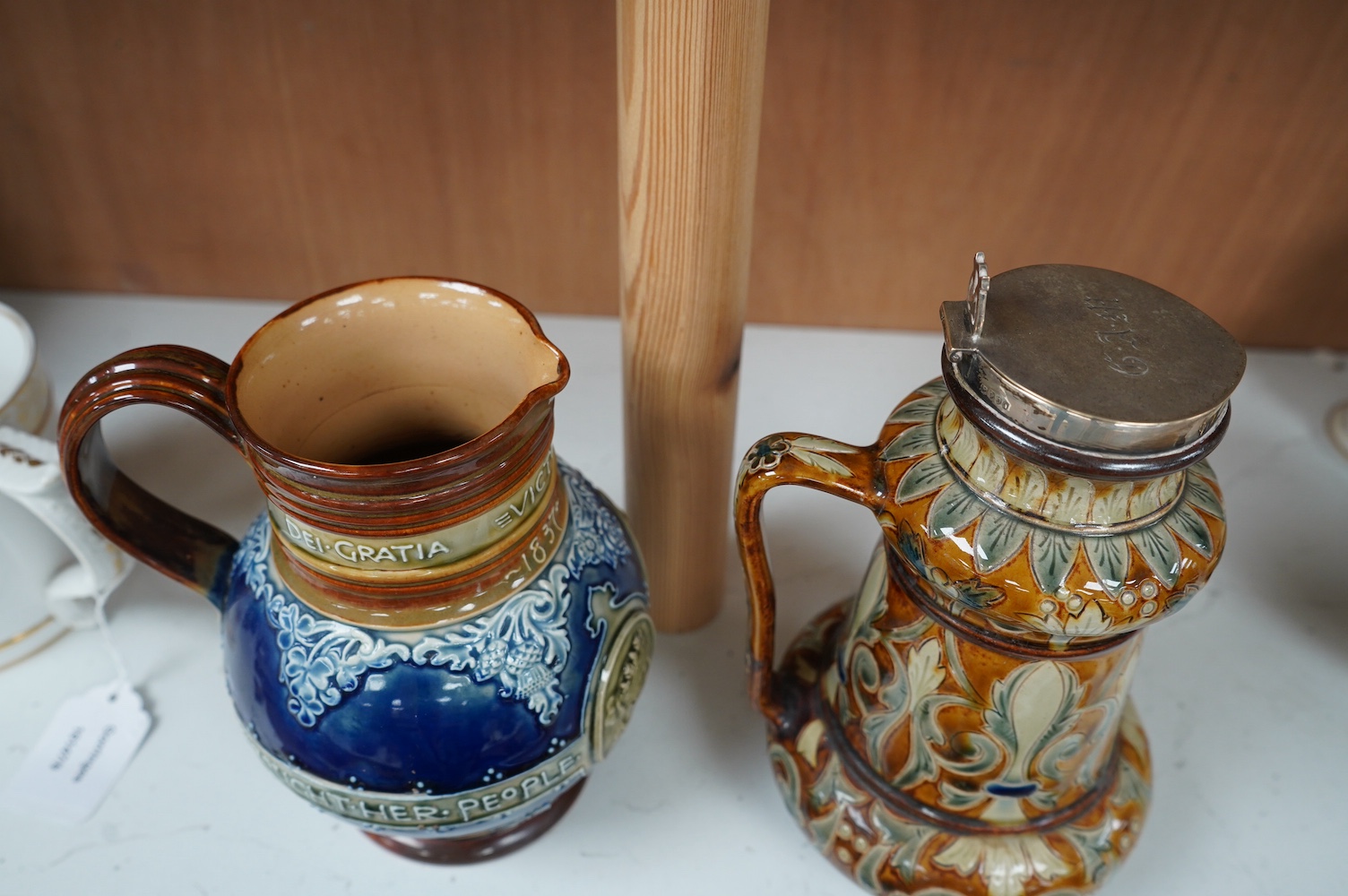 A Doulton Lambeth silver mounted stoneware jug, the silver mount, London 1891, and a Doulton Lambeth Queen Victoria Diamond Jubilee jug, silver mounted jug 21cm high (2). Condition - silver mounting dented